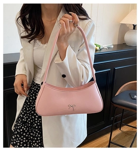 Detailed view of pink leather hobo bag with a decorative silver metal bow accessory