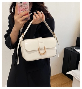 Detail of white baguette bag with golden U-shaped metal buckle and glossy leather finish