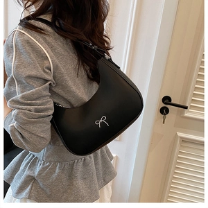 Detail showing the adjustable leather strap and silver bow on the black hobo bag