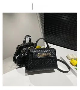 Detail of black trapezoid bag with embossed woven texture and gold twist-lock closure