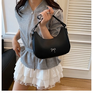 Detail of minimalist black hobo bag with silver bow accent and adjustable shoulder strap