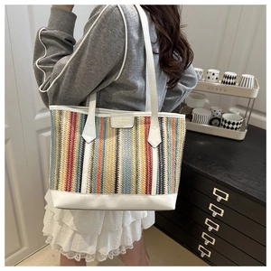 Détail du sac cabas tissé coloré avec des lanières en cuir blanc et motif texturé