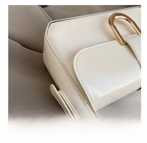 Close-up of premium cream leather bag showing precise stitching and gold U-shaped buckle