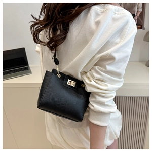 Détail d'un sac à main en cuir grainé noir avec fermoir rotatif doré sur la bandoulière