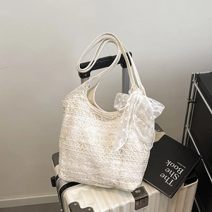Sac fourre-tout élégant en dentelle blanche avec nœud décoratif sur une valise d'été
