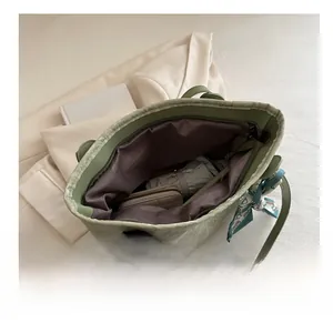 Spacious tote bag interior view with green exterior, purple lining, and silk scarf detail
