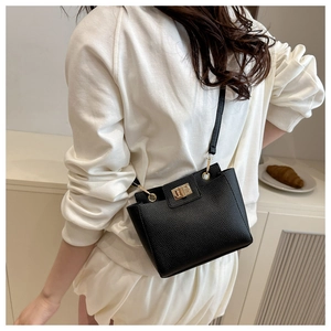 Détail d'un sac bandoulière en cuir grainé noir avec fermoir rotatif doré élégant
