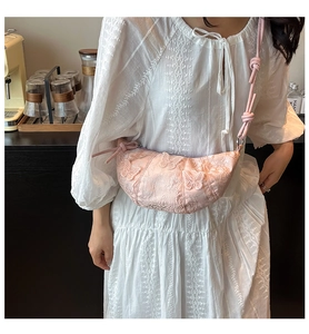 Detailed close-up of pink crescent bag with butterfly embroidery and knotted shoulder strap