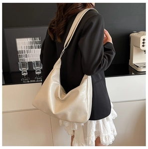 Close-up of a cream oversized hobo shoulder bag showing soft faux leather texture and fit