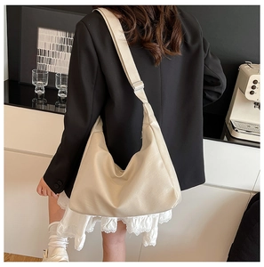 Model wearing a minimalist cream half-moon tote bag with adjustable wide shoulder strap