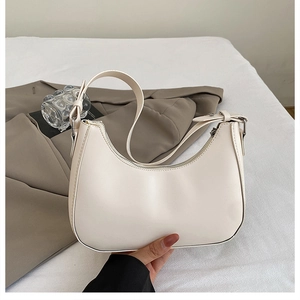 Close-up of a cream leather crescent shoulder bag with silver zipper and matte finish