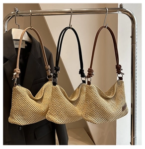 Detail of woven straw tote bags with colorful shoulder straps on metal hangers