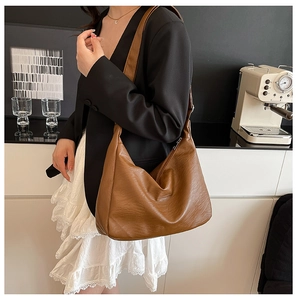 Detail of vintage brown PU leather hobo bag with litchi texture on a model's shoulder