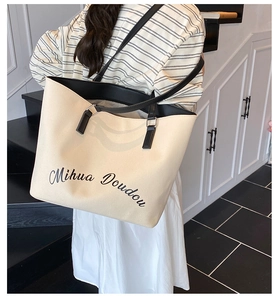 Détail d'un grand sac fourre-tout en toile avec lanières en cuir noir et texte imprimé