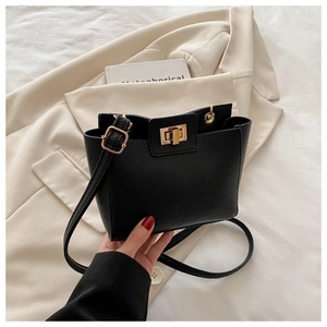 Détail du sac à main noir en cuir grainé avec fermoir rotatif doré et bandoulière