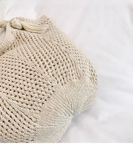 Close-up of cream handmade knit tote bag showing intricate woven texture and soft rope handle