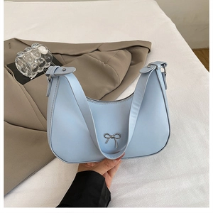 Close-up of light blue crescent bag with silver metallic bow and smooth PU leather texture