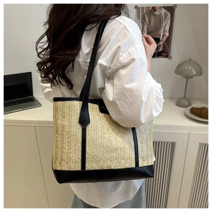 Détail d'un grand sac cabas en paille avec rayures contrastées en cuir noir et anses