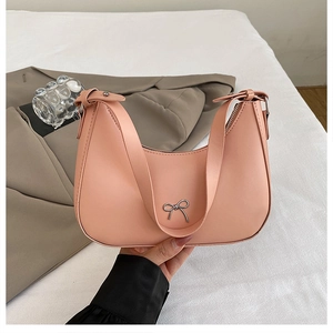 Detail of light pink crescent hobo bag with a silver metallic bow and adjustable strap