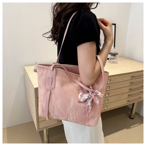 Pink tote bag detail with crinkle texture and decorative silk scarf tied to the handle