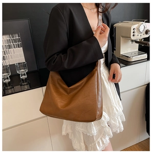 Side view of a vintage brown large leather tote bag worn over the shoulder by a model