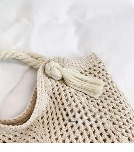 Detail of hand-woven cream cotton shoulder bag with knot tassels and mesh knit texture