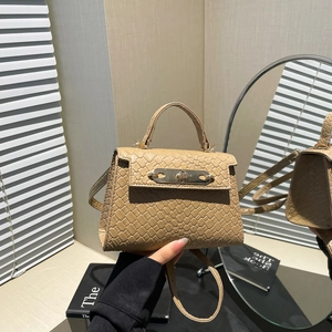 Light brown woven handbag with metal twist lock and shoulder strap in a mirror reflection