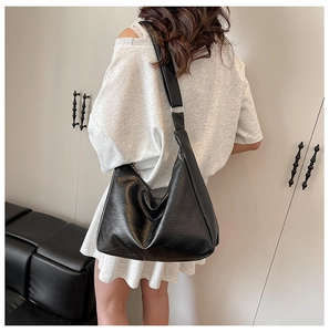 Detail shot of the large black leather tote bag worn by a model in a minimalist setting