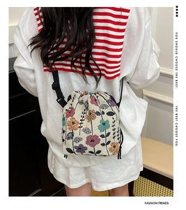 Close-up of floral embroidery detail on canvas drawstring bucket bag with adjustable strap