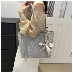 Silver-grey tote bag with pleated metallic texture and a silk scarf detail on the strap