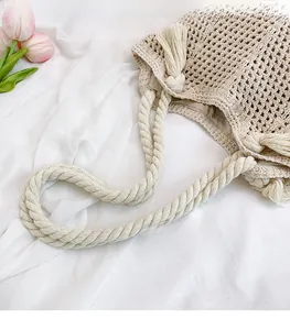 Detailed close-up of woven hollow tote bag featuring cotton rope handles and tassel accent