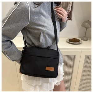Vue détaillée d'un sac à bandoulière minimaliste en nylon noir avec écusson tendance