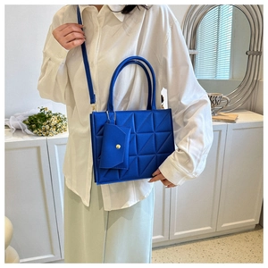 Close-up of a blue quilted handbag with matching pouch shown on a model