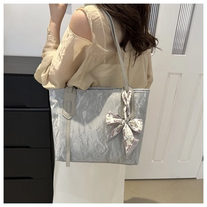 Detail of silver tote bag with pleated texture and fashion printed silk scarf accent