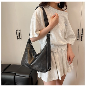 Close-up of the natural leather texture and soft luster on a black oversized hobo tote bag