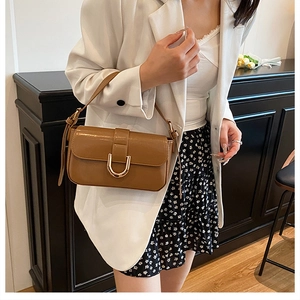 Brown shiny leather underarm bag with a golden U-shaped buckle in a vintage style
