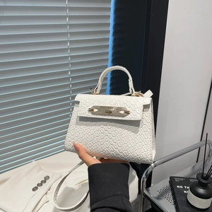 White crocodile pattern handbag with gold lock and adjustable strap in lifestyle setting