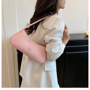 Detail of pink bow shoulder bag on white blazer highlighting minimalist chic design