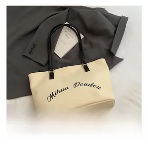 Détail du sac cabas en toile avec anses en cuir noir et logo Mihua Doudou écrit