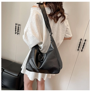 Detailed close-up of large black PU leather tote bag with adjustable strap on shoulder