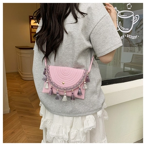 Detail of pink woven crossbody bag with colorful tassels and delicate bohemian lace trim