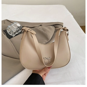 Close-up of apricot crescent underarm bag with silver bow accent and adjustable leather strap