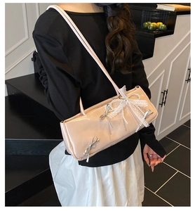 Detail of cream pink shoulder bag featuring lace bow, pearls, and silver ribbon accents