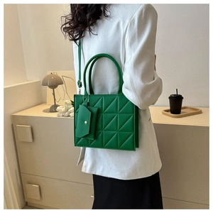 Detail view of a vibrant green quilted handbag with a matching small pouch accessory