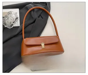 Close-up of brown baguette bag with golden metal buckle and smooth leather texture