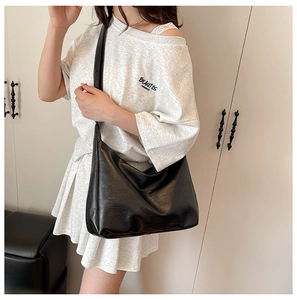 Close-up of a minimalist black matte PU leather tote bag worn on shoulder for commuting