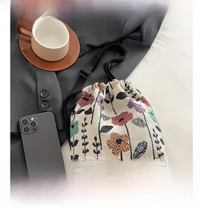 Detail of floral woven bucket bag with drawstring closure and adjustable strap