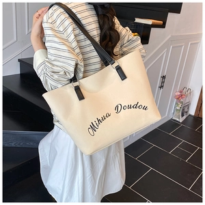 Detail of beige canvas tote bag with black leather straps and Mihua Doudou print