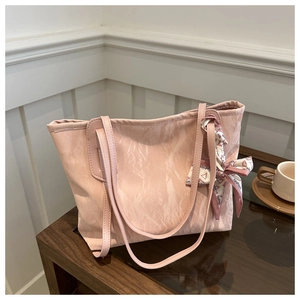 Detailed shot of pink textured tote bag with a silk ribbon scarf and soft lighting