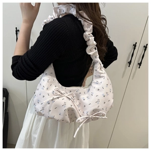 Sac hobo floral avec bandoulière plissée et nœud en ruban bleu porté comme sac d'épaule